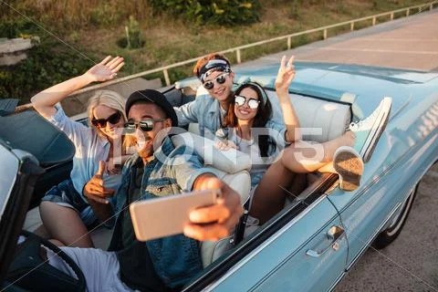 Happy young friends taking selfie with cell phone in car Stock Photos