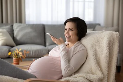 Happy young future mom send voice message using cell Stock Photos