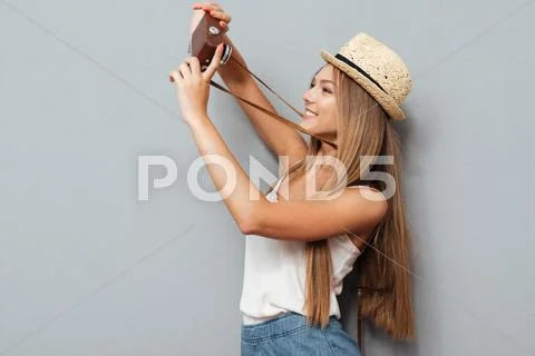 Happy young girl in hat making selfie with retro camera Stock Photos