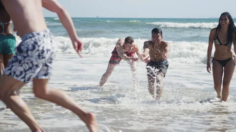Happy young group of multi ethnic friends kicking splashing water on the beach Stock-Footage 51474070