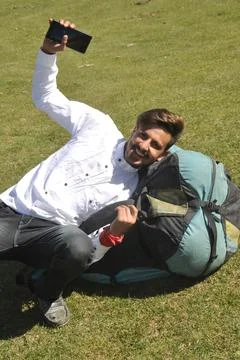 A happy young guy doing fun with lying on Parachute backpack in outdoor  Stock Photos
