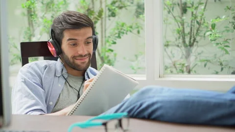 Happy young handsome freelancer man resting with feet on desk while sitting o Stock Footage 134399450