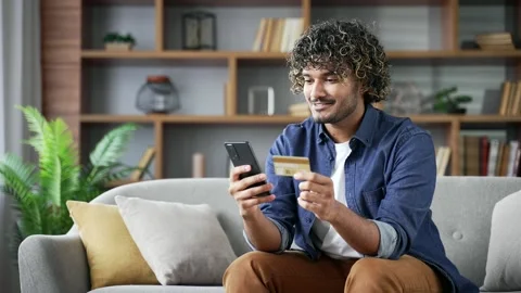 Happy young handsome man doing online shopping typing credit card data on mobile Stock Footage 297866311