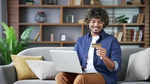 Happy young handsome man doing online shopping typing credit card data on laptop 스톡 동영상 334226071