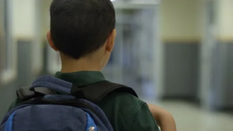 Happy young hispanic student boy with backpack walks down school hall Video stock 142021297
