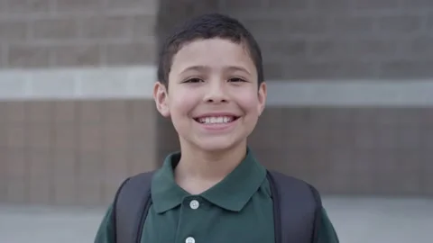 Happy young hispanic student boy smiles at camera outside a school Video stock 142022378