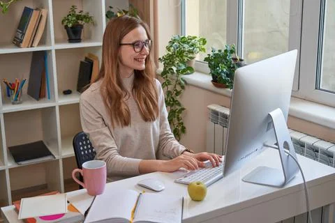 Happy young lady working while looking at computer screen Foto stock