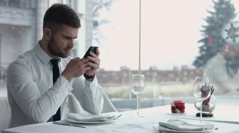 Happy young man browsing internet on smartphone sitting at   cafe Stock Footage 60089827