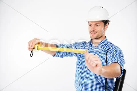 Happy young man building engineer in helmet using measuring tape Stock Photos