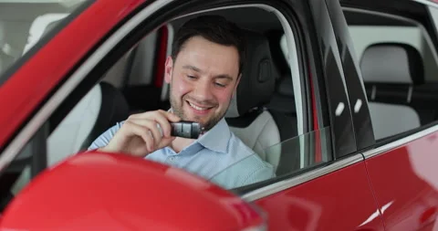 Happy young man in the car getting the keys from the dealer. Concept of car Stock Footage 307690289