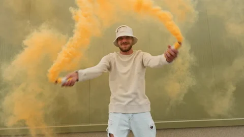 Happy young man dancer moves to music smiling with yellow smoke Stock Footage 155074579