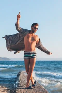 Happy young man dancing on the dock at the beach Stock Photos