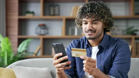 Happy young man doing online shopping typing credit card data on mobile phone  Stock Footage 296757657