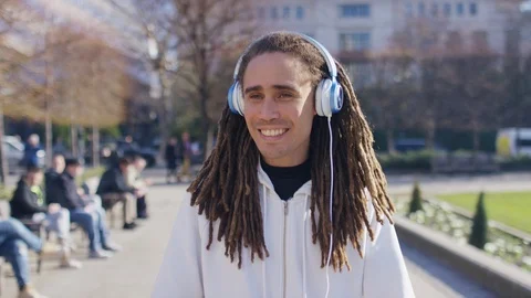 Happy young man with dreadlocks walking and enjoying music on his headphones Stock Footage 103967617