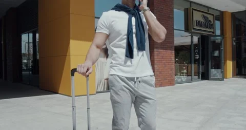 Happy young man, dressed casually, speaking on the phone laying on his suitcase Stock Footage 142286813