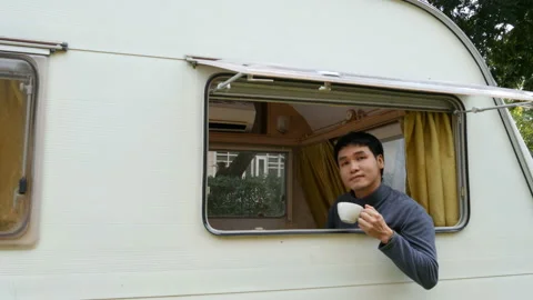 Happy young man drinking coffee at window of a camper RV van motorhome Video stock 153100573