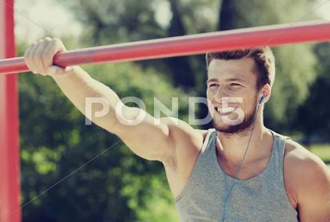 Happy young man with earphones and horizontal bar Stock Photos