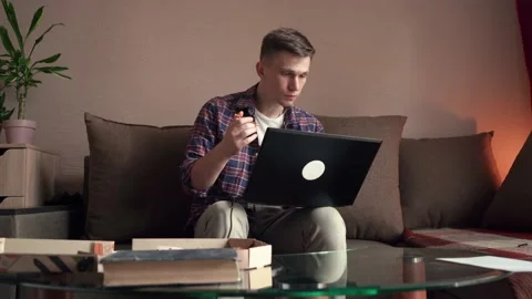 Happy young man eats pizza and works at the computer. home interior. Stock Footage 209306342