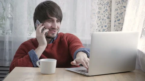 Happy Young Man Freelancer Working with Modern Laptop and Phone in Cafe taking Stock Footage 61930105