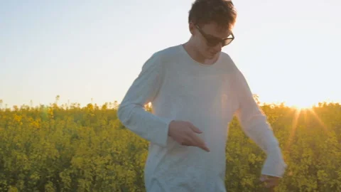 Happy young man having fun and dancing in yellow field during sunset Stock Footage 89449791