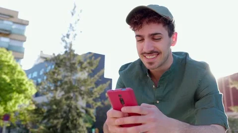 Happy young man having fun using mobile phone relaxing at city street. Stock Footage 283303507