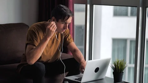 Happy young man in headphones using laptop computer for ecommerce doing online Stock Footage 124886100