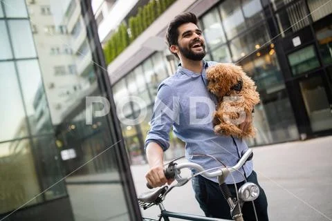 Happy young man holding dog in hands outdoors in city Stock-Fotos