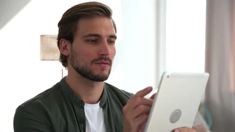Happy young man at home using tablet surfing web, shopping use social media Stock Footage 220865932