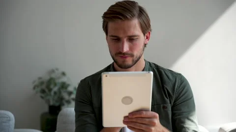Happy young man at home using tablet surfing web, shopping use social media Stock Footage 220866430