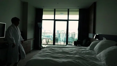 Happy Young Man jump on bed at hotel in bathrobe Stock Footage