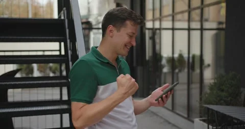 Happy young man looking at cell phone celebrate receiving good news Video stock 273364829