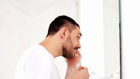 Happy young man looking to mirror at home bathroom Stock Footage