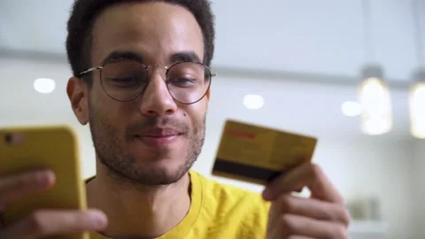 A happy young man making a purchase at an online store using a card and a Stock Footage 167310406
