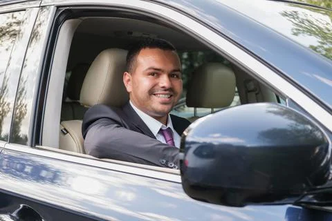 Happy young man of Middle Eastern appearance in business suit is driving an e Stock Photos