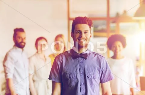 Happy young man over creative team in office Stock Photos