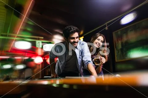 Happy young man playing snooker with his girlfriend. Happy loving couple. Stock Photos