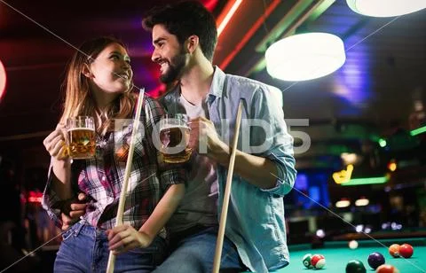 Happy young man playing snooker with his girlfriend. Happy loving couple. Stock Photos