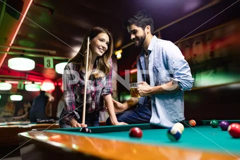 Happy young man playing snooker with his girlfriend. Happy loving couple. Stock Photos