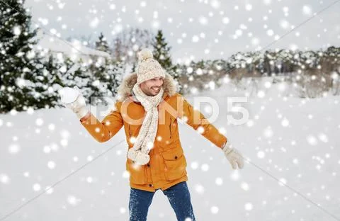 Happy young man playing snowballs in winter Stock Photos