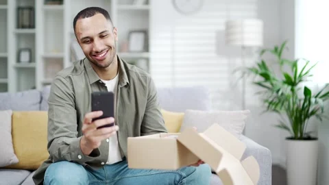Happy young man received parcel order satisfied with shopping in online internet Stock Footage 247073540