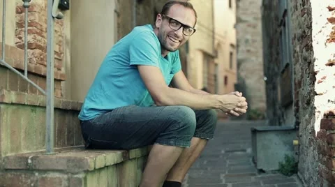 Happy young man sitting on stairs in the city HD Stock Footage