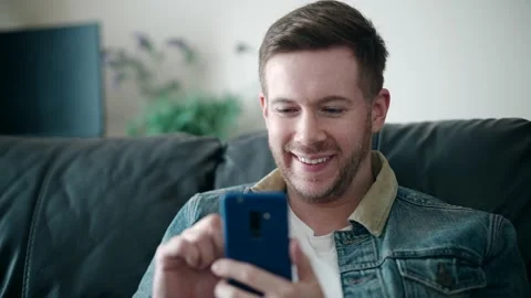 Happy Young Man Smiling Using Mobile Phone At Home, Social Media Stock Footage 153101560
