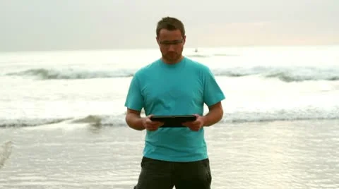 Happy young man with tablet computer on the beach Stock Footage 10758096