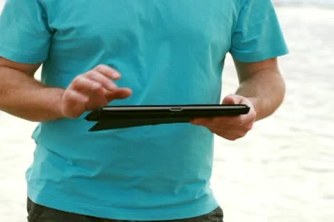 Happy young man with tablet computer on the beach Stockbeeldmateriaal 10791491