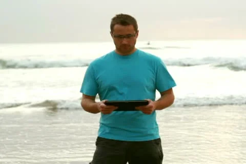Happy young man with tablet computer on the beach Stockbeeldmateriaal 10791510