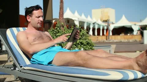 Happy young man with tablet computer lying on sunbed HD Stock Footage 10862706