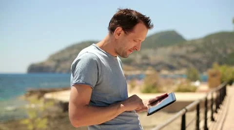 Happy young man with tablet computer, boardwalk by the sea HD Stock Footage