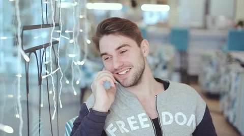 Happy young man talking on cell phone and smile in cafe Stock Footage 58814294