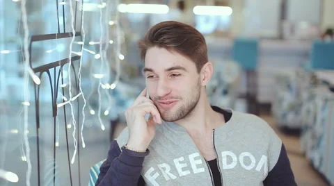 Happy young man talking on cell phone and smile in cafe Stock Footage 65740492