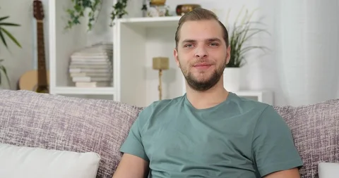 Happy Young Man Talking Looking Camera Pose a Big Laughing Sitting on Home Sofa Stock Footage 85539724